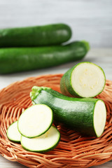 Fresh zucchini on wicker mat on wooden background