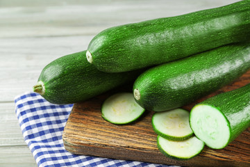 Fresh sliced zucchini on cutting board, on wooden background