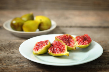 Ripe figs on plate, on wooden background