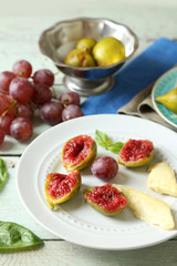 Ripe figs on plate, on color wooden background