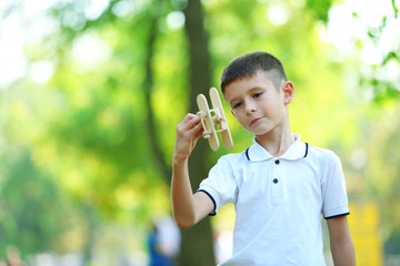 Little boy plays with wooden plane at the park