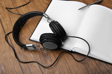 Headphones and notebook on wooden table