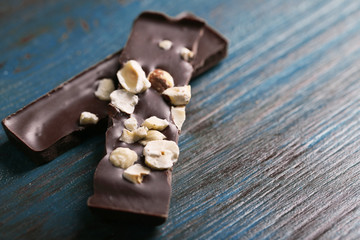 Black chocolate pieces with nuts on color wooden background