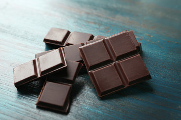 Black chocolate pieces on color wooden background