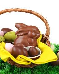 Easter chocolate bunny and eggs on green grass, on white background