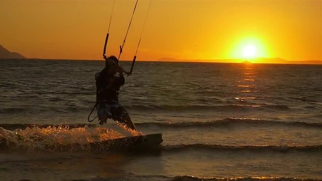 SLOW MOTION: Kiteboarder riding at sunrise