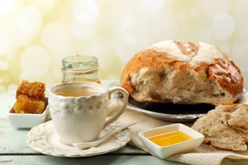 Honeycomb, bowl with honey, cup with herbal tea on color wooden table, on light background