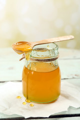 Honey jar with wooden spoon on light background