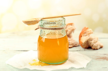 Honey jar with wooden spoon on light background