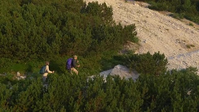 AERIAL: Young couple hiking over scree in the mountains