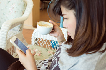 woman drinking hot coffee in cafe and use a mobile phone with bl