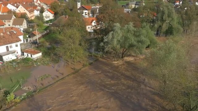 AERIAL: Flooded river running through suburban town