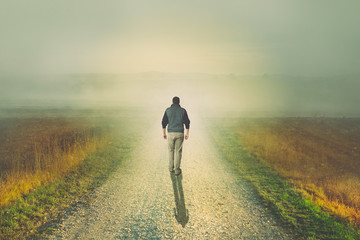 Man walking to the light on a dirt road