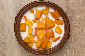 Pumpkin sliced in clay pot with milk