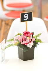 Artificial in black plastic vase on table.