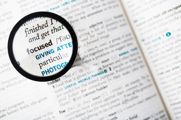 Obraz premium Dictionary definition of the word focused and magnifying glass