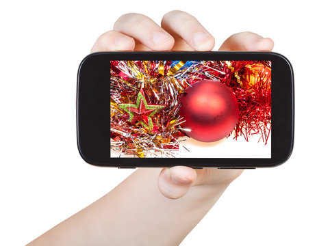 hand holds smartphone with Xmas decorations