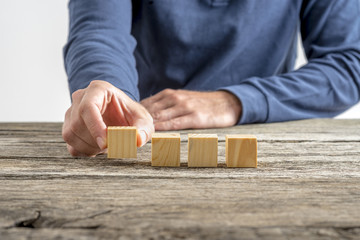 Male hand placing four blank wooden cubes in a row