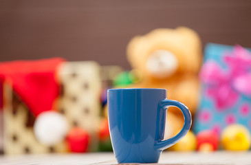Cup with christmas gifts on background