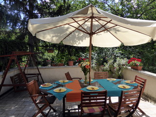 Fototapeta na wymiar Set table below a sunshade in a beautiful green garden