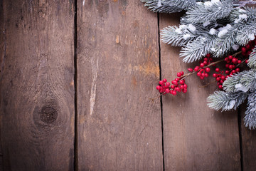 Spruce branches, decorative berries on aged wooden  background.
