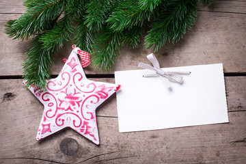 Spruce branches,  Christmas star and empty tag on  vintage  wood