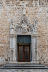 Fototapeta na wymiar Door and statues at the entrance to the Franciscan Monastery at the Old Town in Dubrovnik, Croatia.
