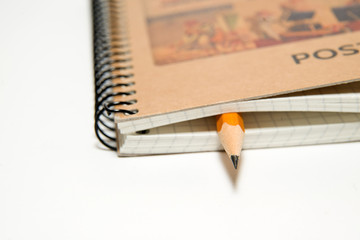 notebook and yellow pencil on over white