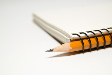 notebook and yellow pencil on over white