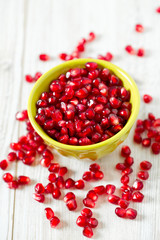 pomegranate seeds in a bowl on wooden surface