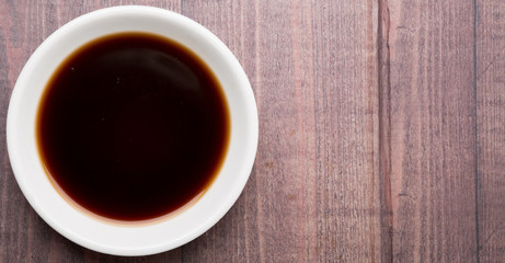 Balsamic vinegar in a white bowl over rustic wooden background
