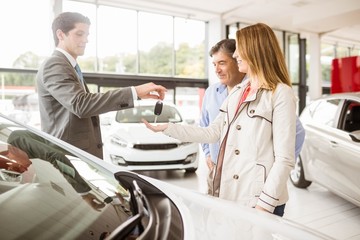 Salesman giving car key to a couple