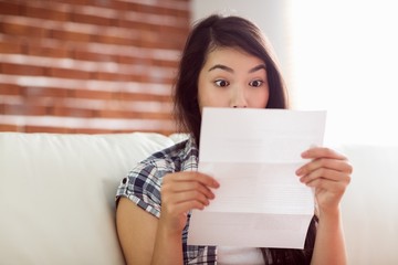 Asian woman on the couch reading letter