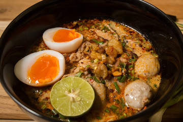 bowl of noodles with vegetables and soft boiled egg on wooden ta