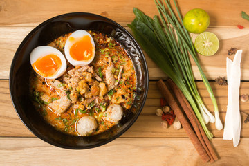 bowl of noodles with vegetables and soft boiled egg on wooden ta