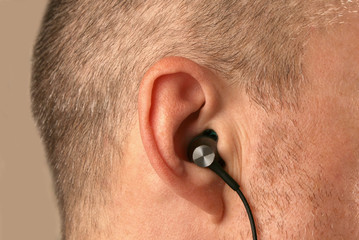 Obraz premium small earphones inserted into the ear of men close up