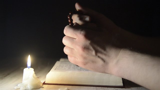 praying hands over a holy book