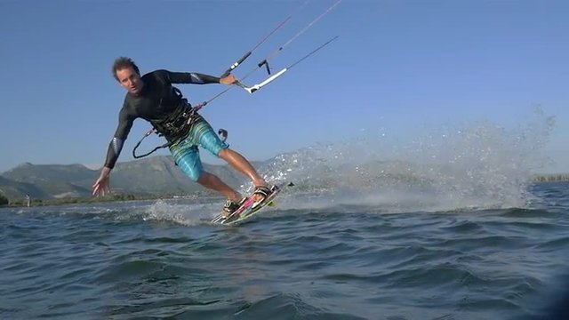 SLOW MOTION: Young kiteboarder riding toeside