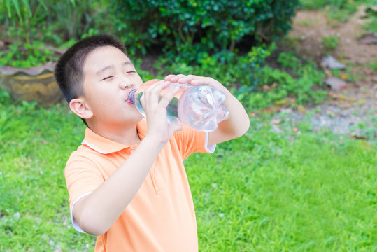 Asian boy drinking water from bottle