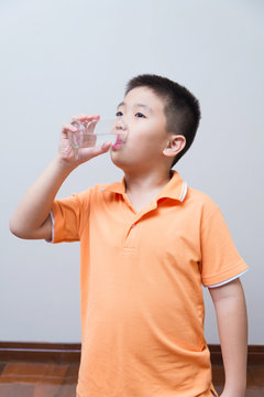 Asian boy drinking water from glass