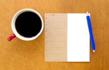 Memory blank notebook and blue pen with coffee on wooden background