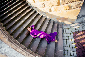Young beautiful girl in the purple dress blue closed eyes lying