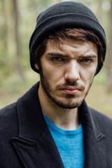young man with black hat in forest