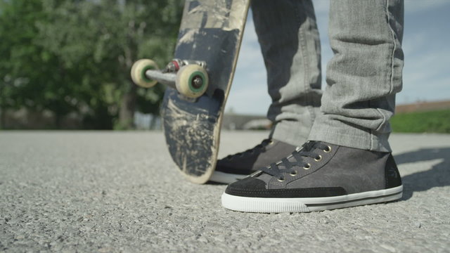 SLOW MOTION CLOSE UP: Skateboarder picking up his skate