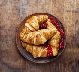 fresh Croissants with Berries on a vintage wooden table.