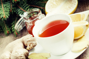 Black tea in a white cup with a lemon, ginger and honey in the b