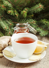 Black tea in a white cup with a lemon, ginger and honey in the b