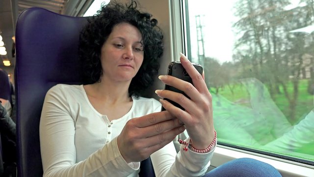Young woman using smartphone while riding train, 