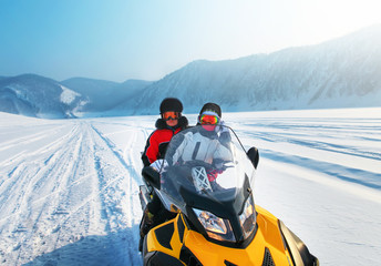 Man and woman riding on snowmobile