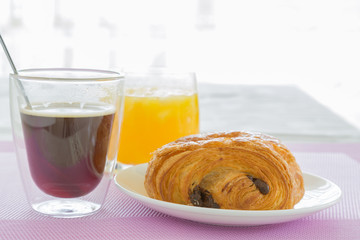croissants with chocolate filling on a white plate, orange juice, coffee. French pastries. side and top view, high key.